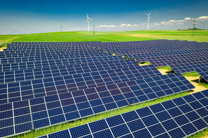 Solar panels, green field and blue sky, aerial view
